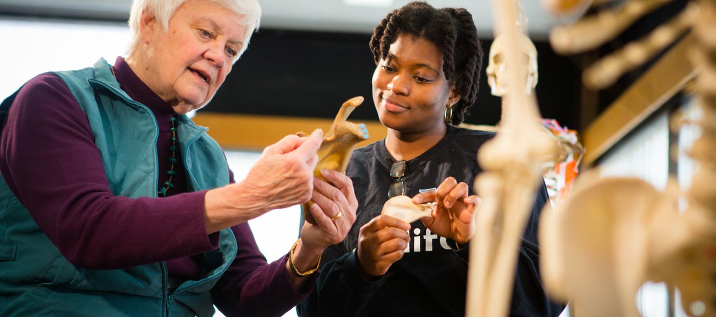 Student examining a bone with a professor