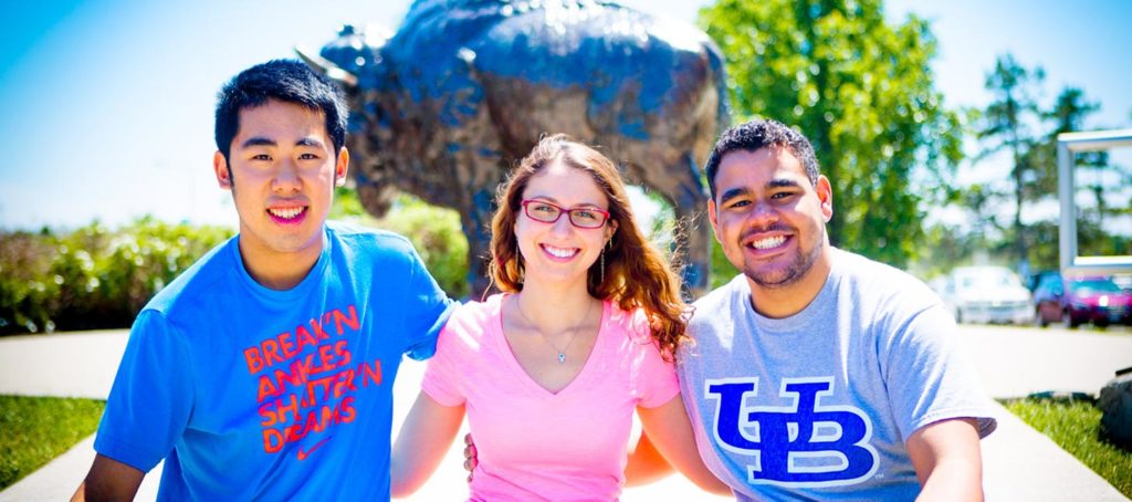 Students posing in front of a buffalo statue on campus