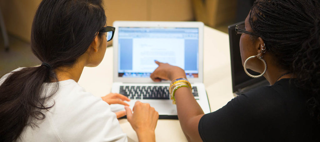 Advising pointing at a computer with a student