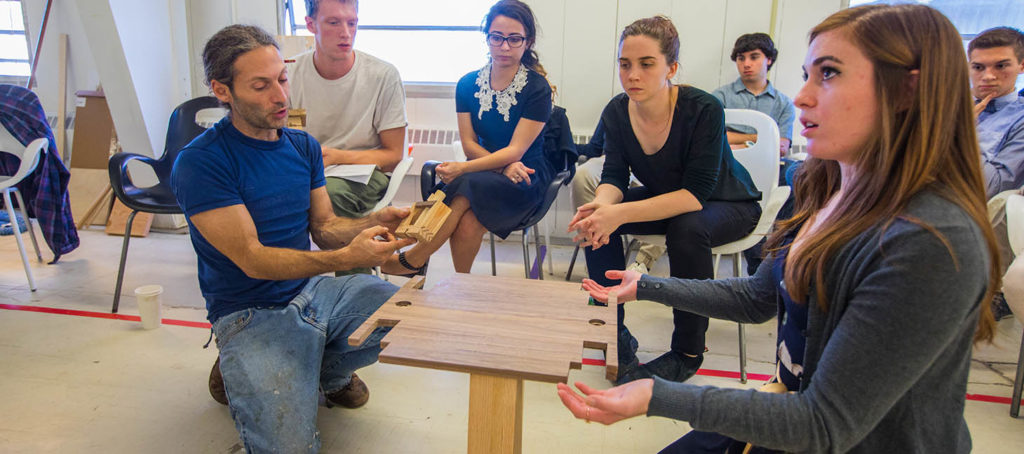 Architecture students examining a wooden base